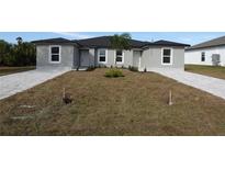 New gray house with gray pavers driveway, landscaping and palm tree at 10402 Pendleton Ave, Englewood, FL 34224