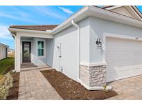 House exterior featuring a light blue facade, white garage door, and a paved walkway at 11277 Boundless Ter, Venice, FL 34293