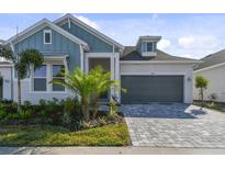 Craftsman style home with gray roof and light blue siding, two-car garage, and a paved driveway at 1578 Running Tide Pl, Sarasota, FL 34240