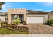 Charming one-story home featuring a stone accent wall, brick driveway, and lush landscaping at 17938 Solstice Ave, Venice, FL 34293