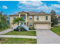 Tan two-story house with a large driveway and palm trees at 1509 Riverside Dr, Tarpon Springs, FL 34689