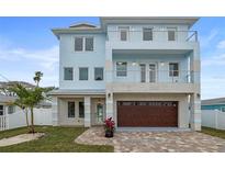 Two-story light blue house with a brown double garage door and a paved driveway at 326 129Th E Ave, Madeira Beach, FL 33708