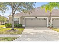 Tan house with a two-car garage and well-manicured lawn at 4427 Ashton Meadows Way, Wesley Chapel, FL 33543