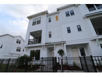 Three-story townhome with white siding, black windows, and a small front yard at 7244 Sutton Ln, Sarasota, FL 34240