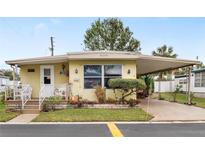 Quaint yellow manufactured home with carport and well-manicured landscaping at 27466 Us Highway 19 N # 103, Clearwater, FL 33761