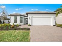 Beautiful single-story home featuring a two-car garage, brick driveway, and manicured landscaping at 17203 Luminous Ave, Venice, FL 34293