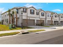 Two-story townhouses with attached garages and landscaping at 31464 Woodland Race Loop, Wesley Chapel, FL 33545