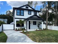 Striking two-story home features black trim, crisp white facade, manicured lawn, and a modern driveway at 4204 N 13Th St, Tampa, FL 33603