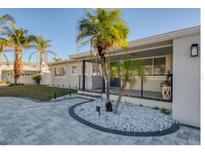 This updated home features a modern exterior, paver driveway, and nicely landscaped entry at 1866 Venetian Point Dr, Clearwater, FL 33755