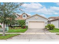 Two-story house with gray siding, a large garage, and a brick paved driveway at 4735 Avila Lakes Dr, Wimauma, FL 33598