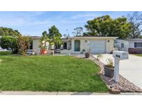 House exterior featuring a well-maintained lawn and single-car garage at 9830 Mark Twain Ln, Port Richey, FL 34668