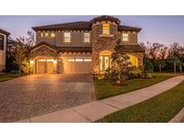 Two-story home with stone accents, three-car garage, and landscaped yard at 13019 Paddock Wood Pl, Riverview, FL 33579