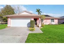 Pink house with a white garage door and a well-maintained lawn at 7853 Sundown Dr, St Petersburg, FL 33709