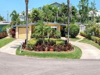 Charming single-story home featuring a circular driveway and lush landscaping with mature palms at 2456 Tradewinds Dr, Dunedin, FL 34698