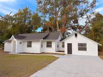 Newly renovated home with a white exterior, fresh landscaping, and a spacious driveway at 6602 N 11Th St, Tampa, FL 33604