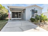 Gray mobile home with covered porch, landscaped yard, and spacious driveway at 3836 Chris Dr, Wesley Chapel, FL 33543