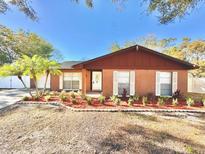 Brick ranch house with landscaped front yard and a red accented roof at 6923 Spanish Moss Cir, Tampa, FL 33625