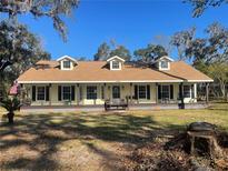 Yellow house with brown roof, front porch, and landscaped yard at 1315 Cowart Rd, Plant City, FL 33567