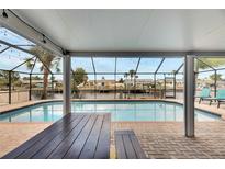 Screened-in pool overlooking the water with brick deck, outdoor table, and string lights at 1011 Spindle Palm Way, Apollo Beach, FL 33572