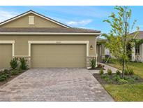 Tan two-car garage home with paved driveway and landscaped walkway at 20363 Symphony Pl, Venice, FL 34293