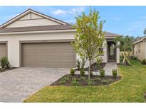 New construction home exterior with two-car garage and landscaped yard at 20375 Symphony Pl, Venice, FL 34293