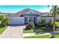 Beautiful two-story house with gray roof, light blue exterior, and a paver driveway at 11521 Lake Lucaya Dr, Riverview, FL 33579