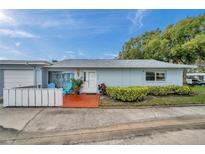 Charming single-story home featuring a tidy front yard, patio with colorful seating, and an attached garage at 1606 Berwick Ct # 10B, Palm Harbor, FL 34684