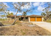 House exterior with double garage and mature landscaping at 945 Bayshore Dr, Tarpon Springs, FL 34689