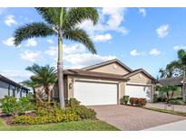 Tan two-car garage villa with landscaping and a paved driveway at 20644 Swallow Tail Ct, Venice, FL 34293