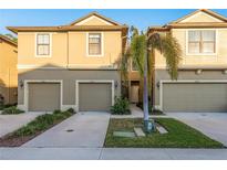 Tan two-story townhome with a two-car garage and lush landscaping at 5162 Bay Isle Cir, Clearwater, FL 33760
