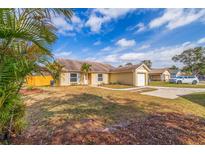 Cute yellow house with a landscaped yard and attached garage at 1930 Castle Bay Ct, Oldsmar, FL 34677