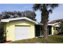 Ranch style home with attached garage and palm tree in front yard at 105 Causeway Blvd, Belleair Beach, FL 33786