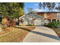 Gray house with attached garage and long driveway, surrounded by lush green landscaping at 9402 Forest Hills Cir, Tampa, FL 33612