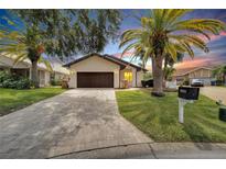 Single-story home with a dark brown garage door, paver driveway, and landscaping at 6208 Spoonbill Dr, New Port Richey, FL 34652