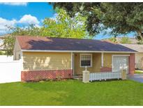 Tan house with brick accents, attached garage, and landscaped yard at 14010 Fullerton Dr, Tampa, FL 33625