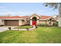 Single-story home with red door, tile roof, and landscaped lawn at 161 Woodcreek N Dr, Safety Harbor, FL 34695