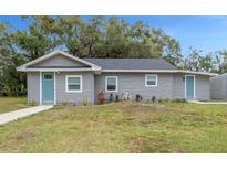 Newly renovated gray house with teal door, walkway, and grassy yard at 2812 Tom Brewer Ln, Plant City, FL 33566