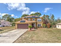 Two story home features an attached garage and solar panels at 2359 Gimlet Ave, Spring Hill, FL 34608