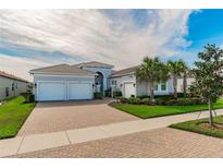 Two-story house with gray exterior, two-car garage, and landscaped front yard at 4919 Pamplona Ct., Wimauma, FL 33598