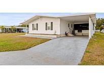 White single-wide manufactured home with carport and landscaped lawn at 36925 Kiowa Ave, Zephyrhills, FL 33542