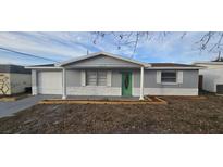 Newly painted gray house with a green door, white garage door and landscaping at 5021 Chet Dr, New Port Richey, FL 34652