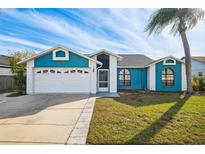 Cute blue house with a white garage door and well-manicured lawn at 8436 Red Roe Dr, New Port Richey, FL 34653