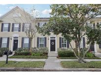 Tan three-story townhome with black shutters and a lush green lawn at 9910 New Parke Rd, Tampa, FL 33626