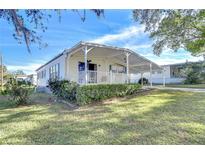 Single-wide mobile home with covered carport and landscaped yard at 6130 Crestview Ln, Zephyrhills, FL 33542