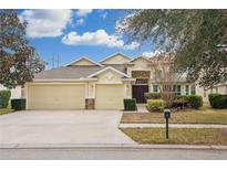 House exterior featuring a three-car garage and well-manicured landscaping at 15719 Starling Water Dr, Lithia, FL 33547