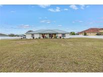 Single-story house with green roof, large yard, and white fence at 2413 Crestview Rd, Wimauma, FL 33598