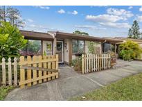 Front view of charming condo with a white picket fence and well-manicured landscaping at 106 Edgewood Ct, Oldsmar, FL 34677