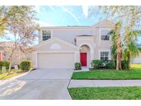 Two-story house with red door, attached garage, and landscaped lawn at 13167 Royal Pines Ave, Riverview, FL 33579