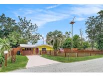 Cute yellow house with a wooden fence and well-maintained lawn at 4045 Cranbrook Pl, New Port Richey, FL 34652