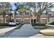 Tan three-story townhouse with two-car garage and landscaping at 4950 Pond Ridge Dr, Riverview, FL 33578